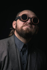 Obraz premium charismatic man in a classic suit and steampunk goggles on a black background stylish Portrait