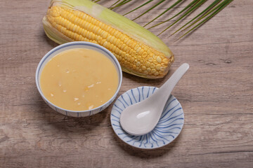 Sweet corn soup in a ceramic cup on wooden background.