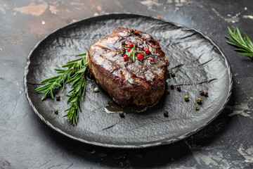 Grilled meat steak Filet Mignon with seasonings. Juicy meat steak on a dark background. Food recipe...