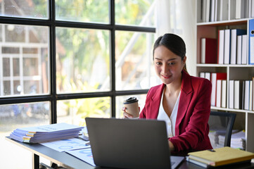 Professional millennial Asian businesswoman working at her desk in the office, using laptop