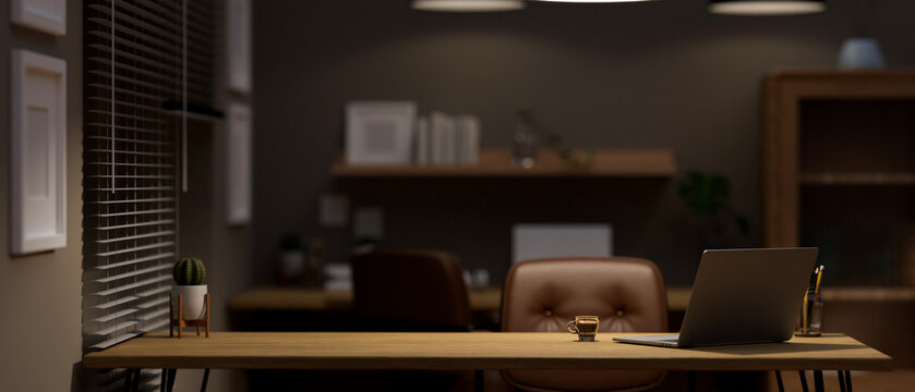 Copy space on wooden desk with laptop, coffee cup and decor in modern home office at night