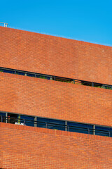 Wall of brick with orange color in the downtown city with some visible windows in a horizontal row