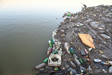 Water pollution. Garbage floating in contaminated river. Plastic bags, bottles, and trash dumped in the river. Environmental disaster.