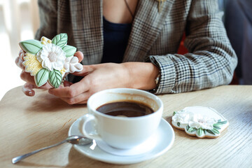 Delicious, appetizing, tasty gingerbread cake with mastic cream in flower shape near coffee cup on wooden table in cafe