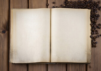 Top view of blank old book with cofee beans on vintage wooden table