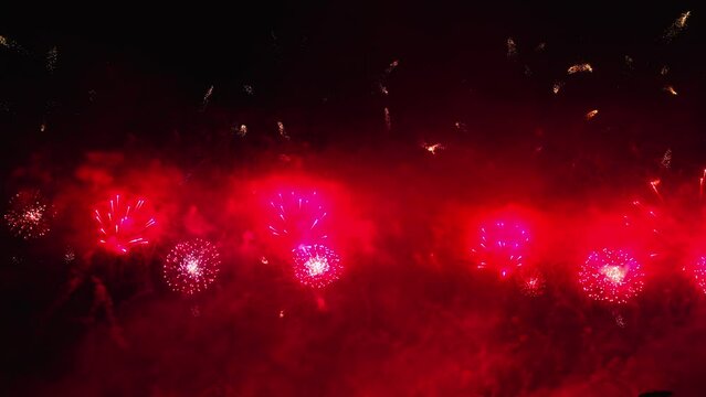 Colorful fireworks festival. Beautiful red fireworks close-up view in slow motion. Wonderful real fireworks in the night sky shot with a telephoto lens. fireworks show. 4K slow motion video.