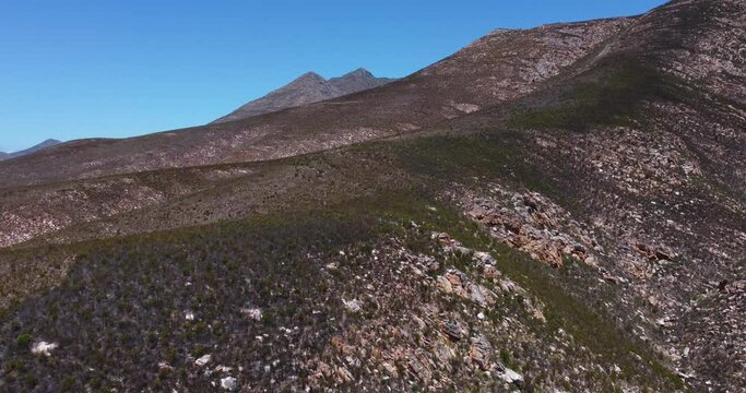Tracking Shot Flying Forward and turning left, over dessert mountains with rocks and small bushes, at Cloetesberg, on edge of the klein karoo semi desert region and garden routes, South Africa.