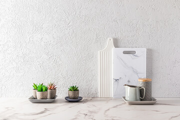 part of the interior of a modern kitchen countertop with white marble cutting boards and succulents in flower pots. minimalism.