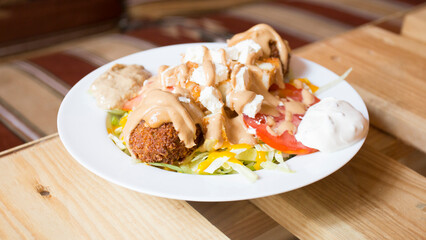 Falafel combo dish with vegetables. Faláfel or falafel​ is a chickpea or broad bean croquette. It is usually consumed in the Middle East.