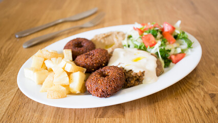 Falafel combo dish with vegetables. Faláfel or falafel​ is a chickpea or broad bean croquette. It is usually consumed in the Middle East.