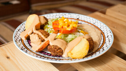Falafel combo dish with vegetables. Faláfel or falafel​ is a chickpea or broad bean croquette. It is usually consumed in the Middle East.