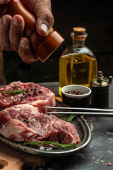 Pork steak and salt by the chef. Backstage of preparing grilled pork meat. Culinary, cooking concept. place for text