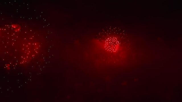 Colorful fireworks festival. Beautiful red fireworks close-up view in slow motion. Wonderful real fireworks in the night sky shot with a telephoto lens. fireworks show. 4K slow motion video.