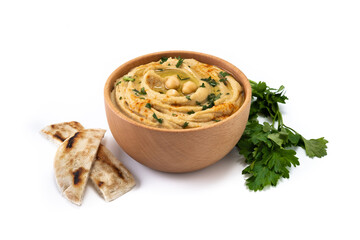 Chickpea hummus in a wooden bowl garnished with parsley, paprika and olive oil isolated on white background