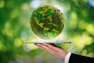 A man is holding a digital tablet. Above this green planet Earth. Symbol of sustainable development...