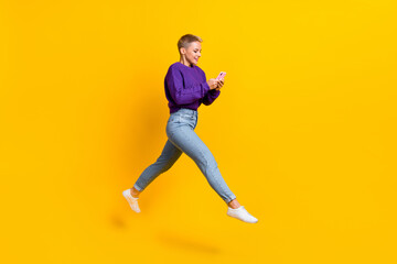 Fototapeta na wymiar Full length profile photo of active excited person run jump use telephone isolated on yellow color background