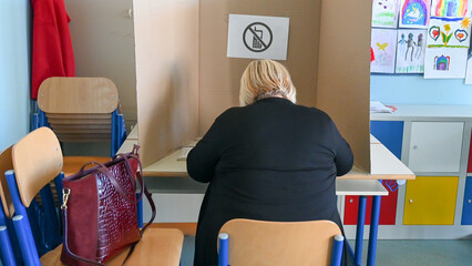 A woman in a voting booth. Citizens vote in elections. Voters on election day. Citizens casting...