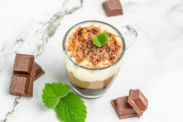 Mousse Three chocolates in a glass decorated with mint on a light background. Layered delicious dessert. place for text, top view