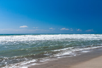 Fototapeta na wymiar Coast of Mediterranean Sea. Turquoise foamy waves. Sand beach. Close-up. Sunny autumn day. Fethiye, Turkey.