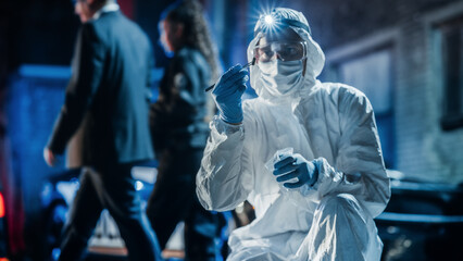 Forensics Technician in Coveralls Inspecting Potential Incriminating Evidence on Crime Scene. He...