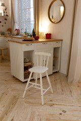 children's white chair in the kitchen in Scandinavian style. Christmas lights on the window