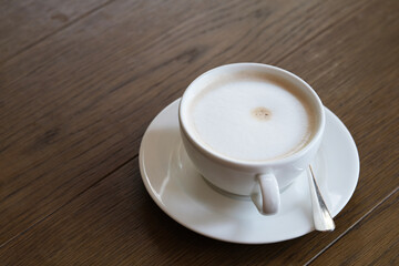 close up white cup of latte coffee on wooden table