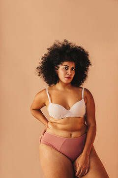 Self-confident woman with an Afro hairstyle wearing underwear in a studio