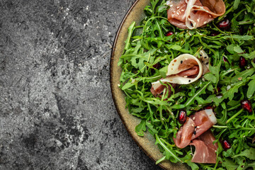 Salad with Serrano jamon, ham, rucola on Black background, top view