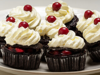Black forest cakes, Schwarzwald. Cakes with dark chocolate, whipped cream and cherry on a plate.