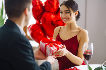 Exchange of gifts. Young couple celebrating Valentine's Day.Romantic evening in a restaurant.