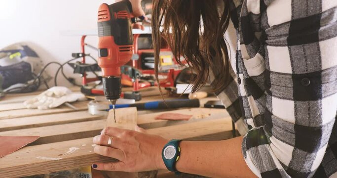 Carpenter woman drilling wood, close up 4k video