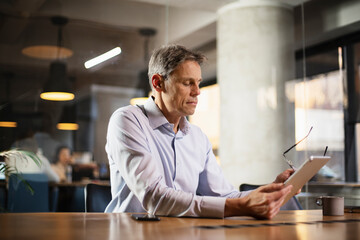 Fototapeta premium Portrait of businessman in office. Man using digital tablet. Businessman having video call.