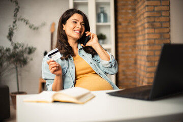 Pregnant woman shopping online at home. Happy woman with laptop and credit card