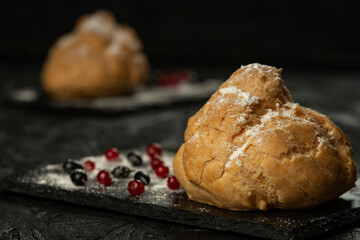 Freshly baked big eclair on a black cutting board