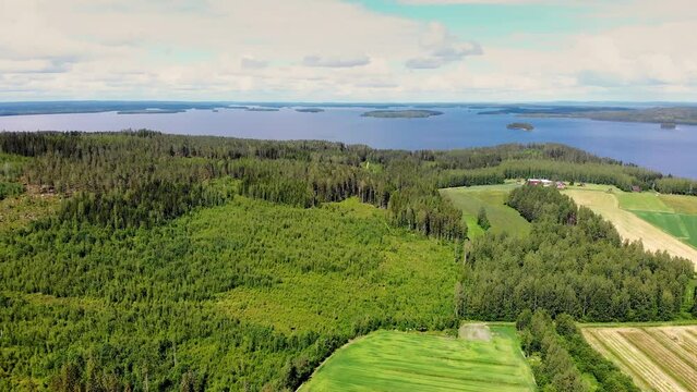 Aerial view of Finnish countryside and forest with a lake and islands in the background on a summer day