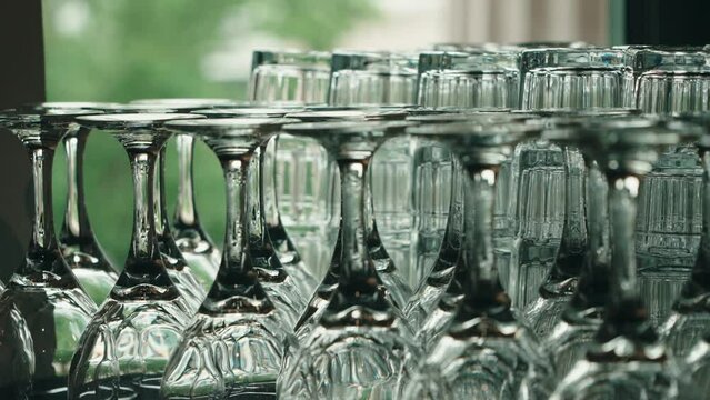 Rack focus on neatly arranged wine and drink glasses for a formal event.  This shot works great for a wedding, corporate event, or restaurant scene.  Beautiful abstract reflections and color.