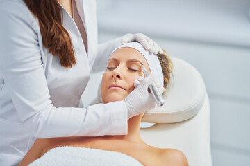 Fototapeta na wymiar Woman having permanent eyebrows cosmetology treatment in salon