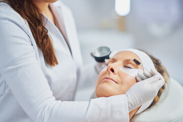 Woman having cosmetology eyebrows treatment in beauty salon