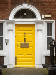 Colorful yellow door in old Dublin, Ireland. Entrance to Georgian style buildings in high value property area of the capital.