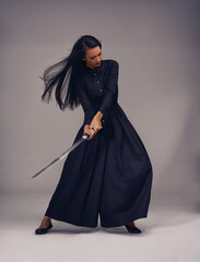 Samurai, sword and japanese woman fighter, ninja or warrior swing to fight for power, cosplay and fantasy. Asian female from Japan in black fashion with beauty, action and metal weapon for art deco © Tasneem/peopleimages.com