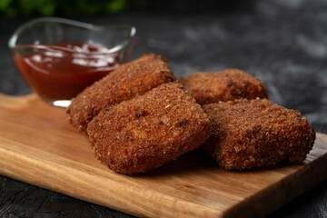 chicken nuggets and sauce on a board .
