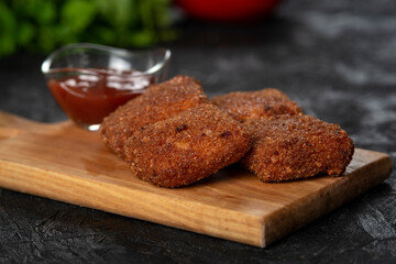 chicken nuggets and sauce on a board .