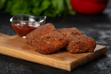 chicken nuggets and sauce on a board .