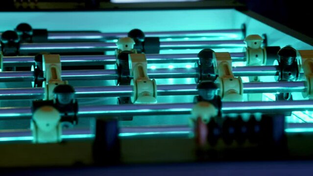 Slow pan of an led-backlit foosball table.  The ball flies back and forth as the players compete against each other.  A club or sci-fi vibe is perfect for this futuristic looking game.
