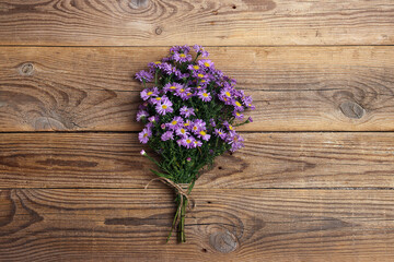 Fototapeta na wymiar Bouquet of small purple asters on old wooden boards.