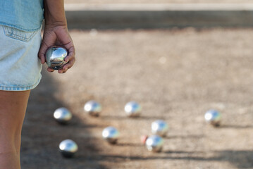 Senior playing petanque un and relaxing game, balls on the ground. Senior woman prepared to throw...
