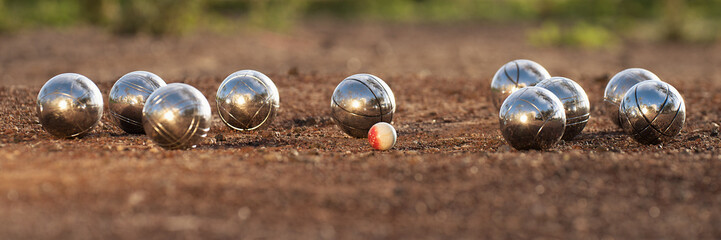 Petanque balls boules bowls on closeup on sand gravel court background, game of petanque on the ground. Balls and a small wood jack