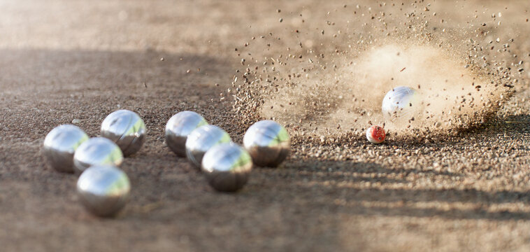 Petanque ball boules bowls on a dust floor, photo in impact. Game of petanque on the ground. Balls and a small wood jack