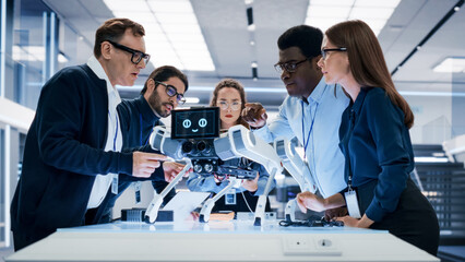 Portrait of a Young Team of Multicultural Engineers Use Computers, Insert a Circuit Board, Analyze...