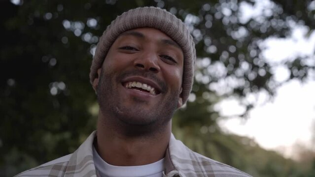 Portrait of mixed race man smiling and looking at camera. Friendly happy African American male person outdoors. Close up.